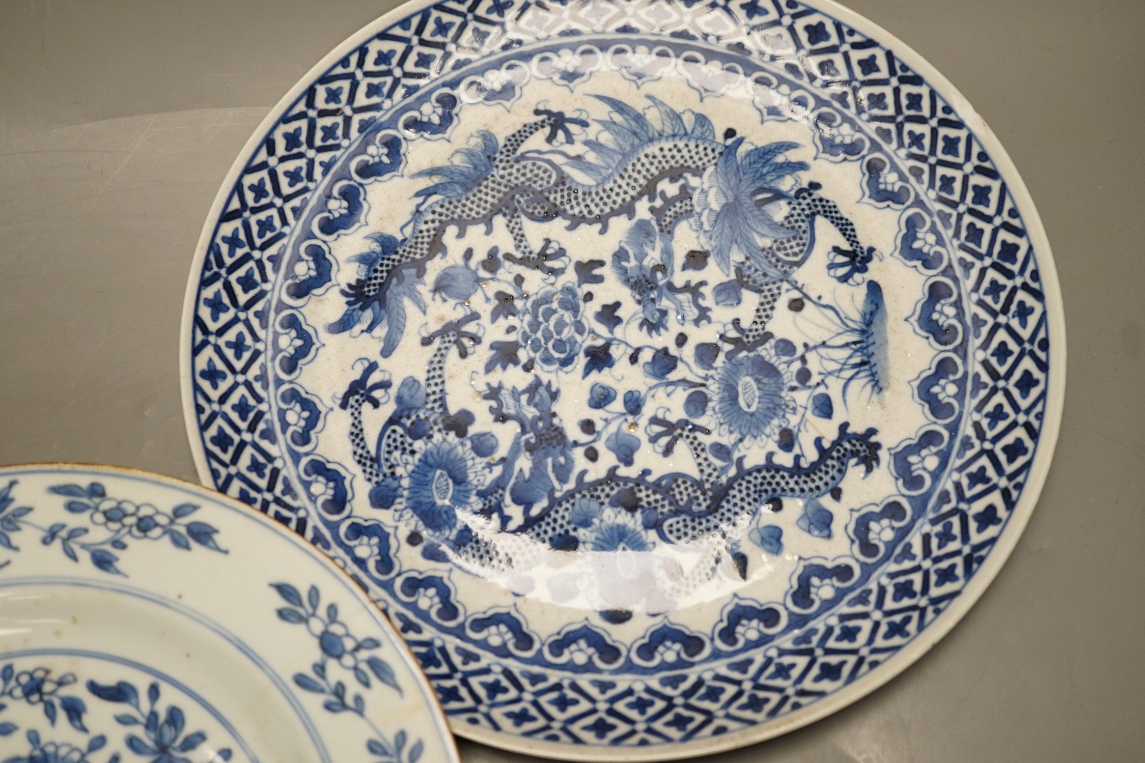 Four Chinese 18th century plates and a late 19th century blue and white dragon plate, largest 24cm diameter